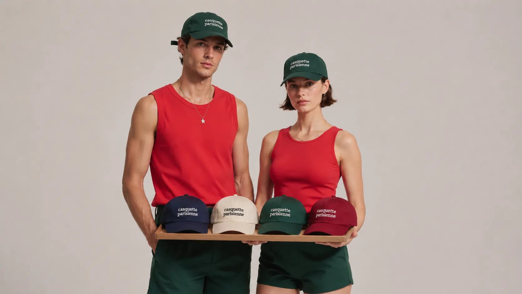 Deux membres d'une équipe en tenue assortie portant des casquettes vertes brodées, plateau de quatre coloris de casquettes personnalisées : marine, écru, vert, bordeaux